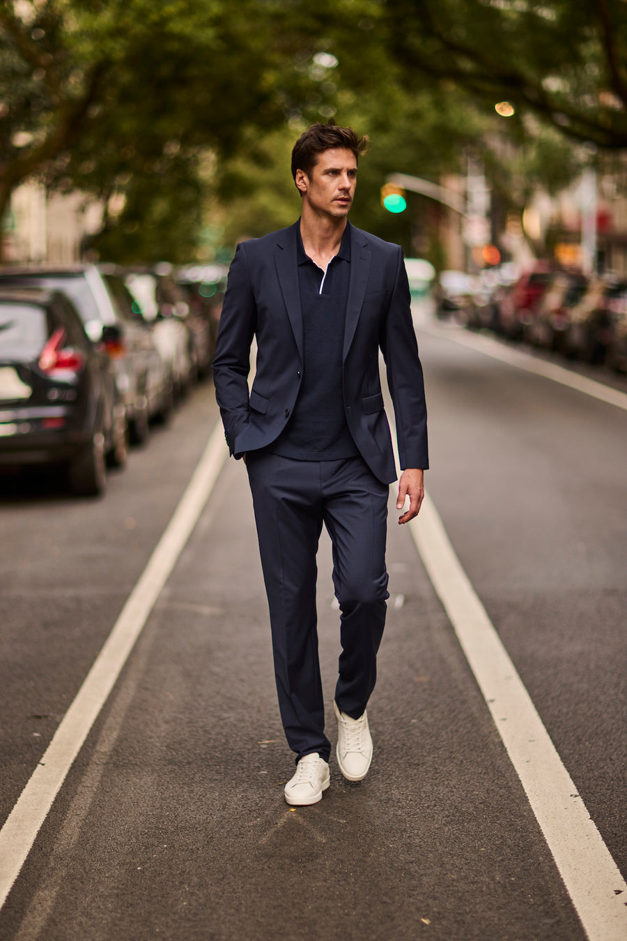 A man in a navy suit walking a city street in Deming shoes